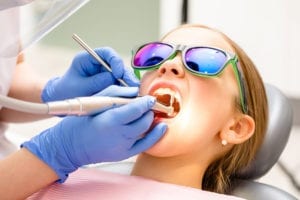 young girl in dental chair whose teeth are being cleaned