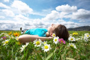 Woman lying in a field of flowers under a beautiful blue sky. 
